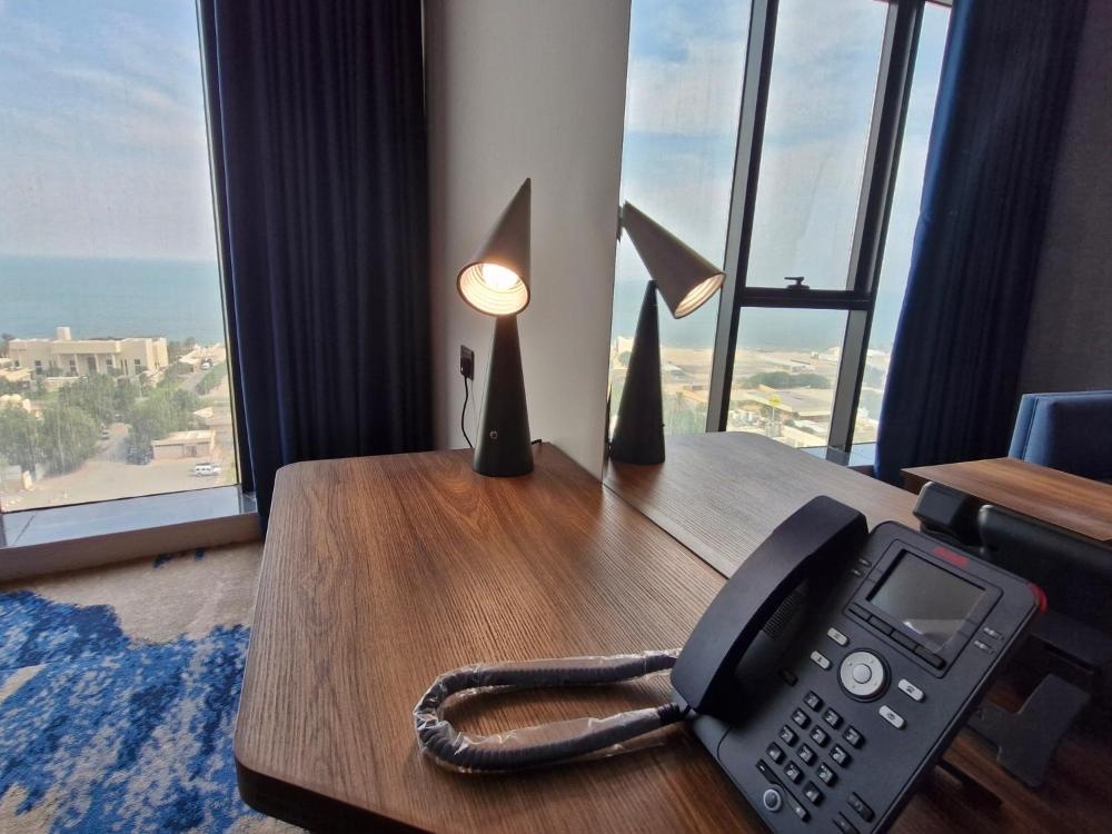 Desk with phone and lamps overlooking city at Ocean View Hotel Kuwait